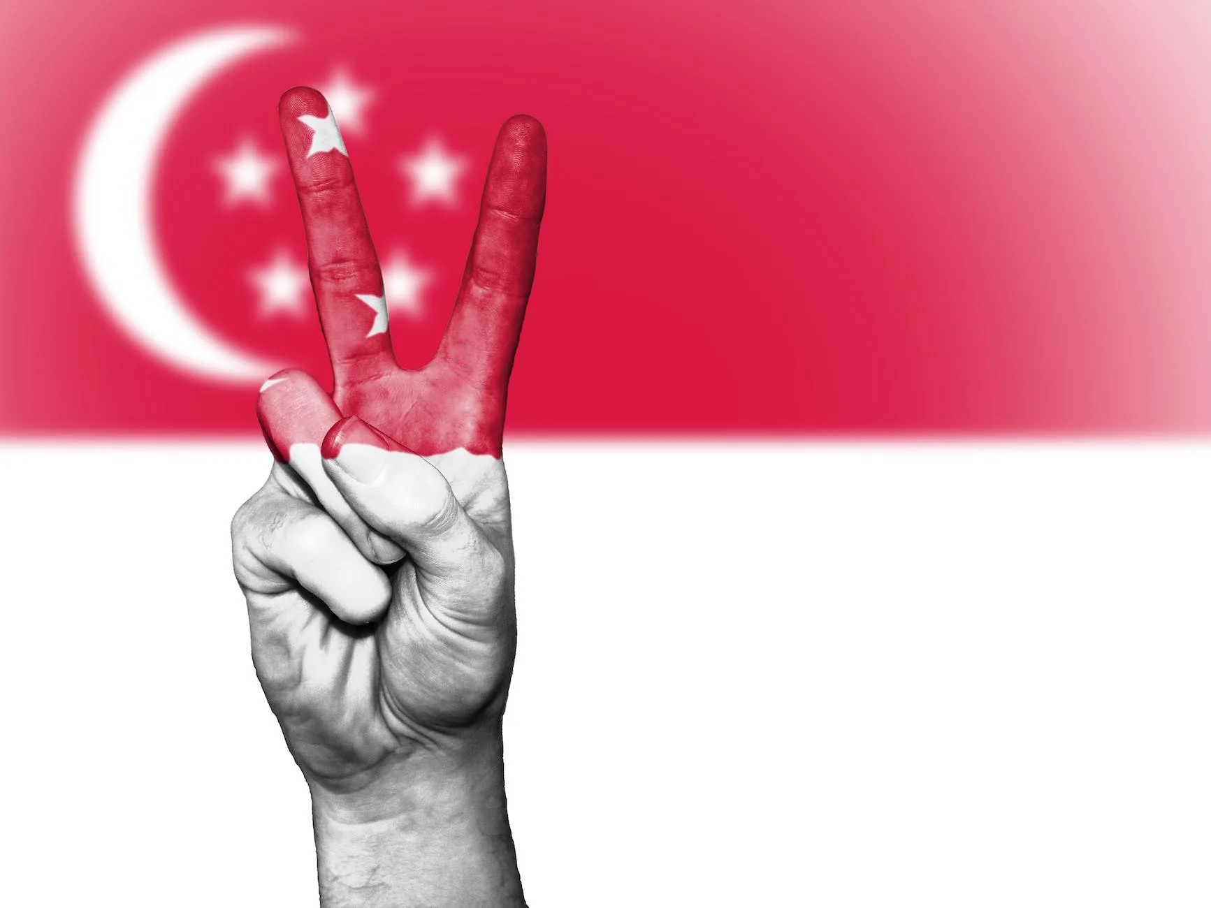 singapore flag themed painted hand in peace sign gesture